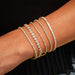 Diamond Bezel Eternity Bracelet in 14k yellow gold styled on wrist with four diamond tennis bracelets