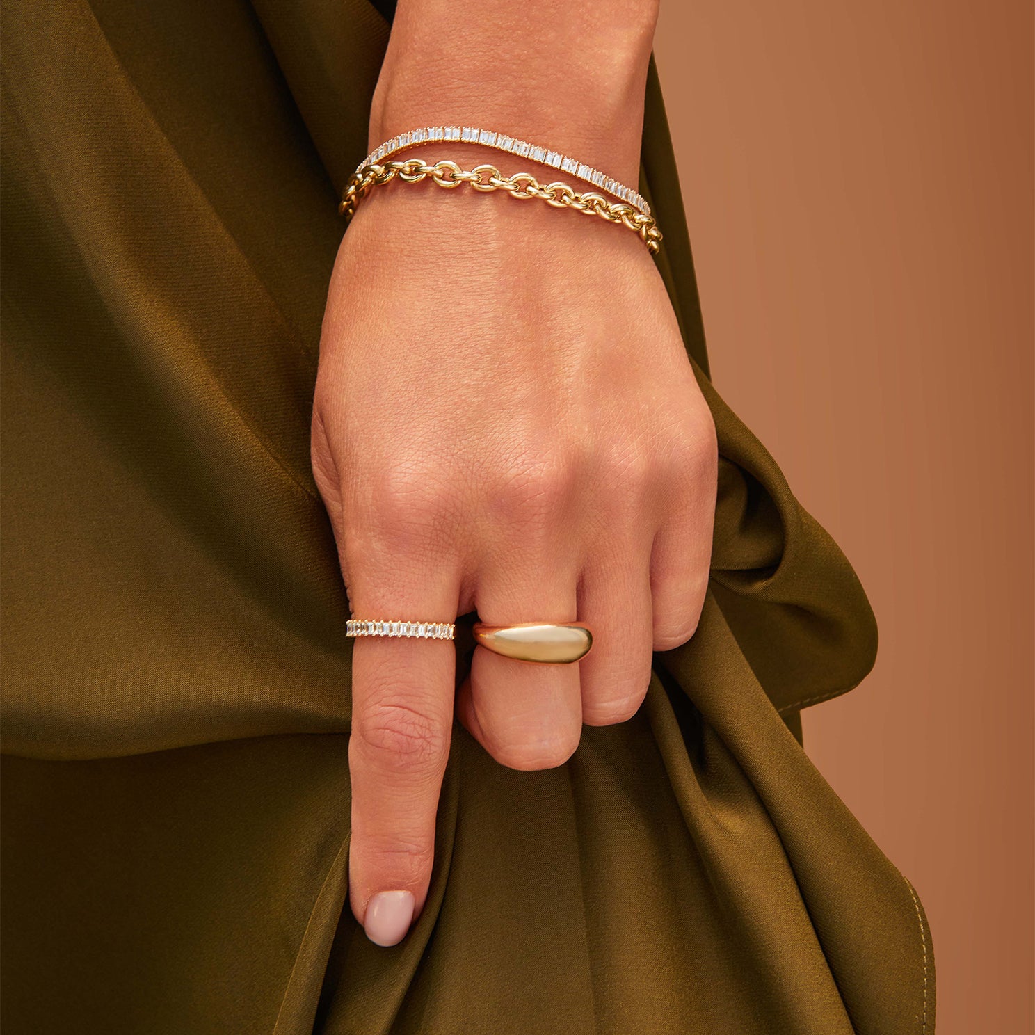 Prong Set Diamond Baguette Ring styled on index finger of model with bracelets and gold ring