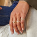 Diamond Swirl Ring stlyed on pinky ring of model with three diamond and gold rings