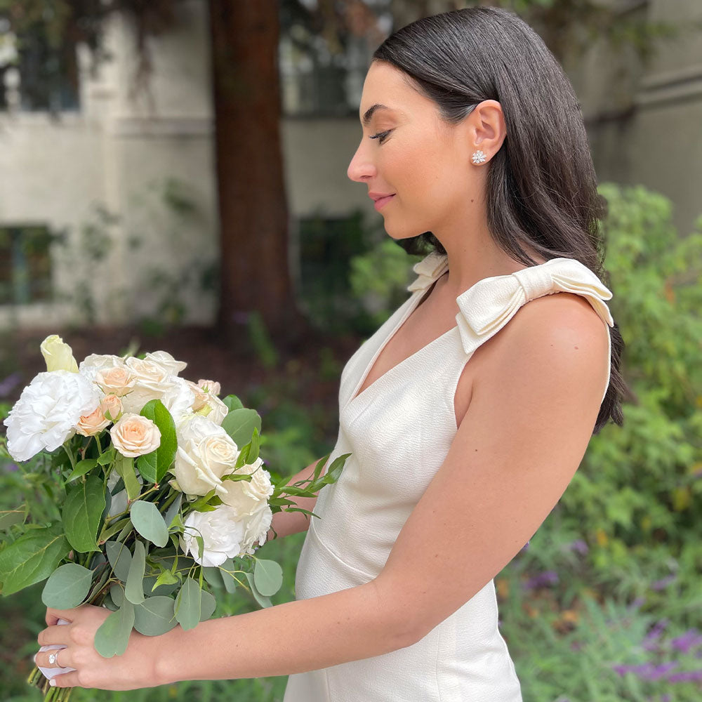 EF Collection diamond earring styled on ear of model in white dress