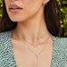 Full Cut Diamond Teardrop Necklace in 14k yellow gold styled on neck of model with two gold and diamond necklaces. Model in green and white top