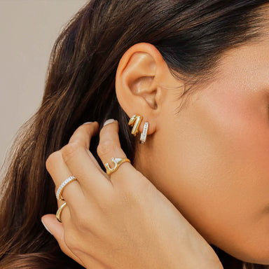 Double Gold Jumbo Huggie Earring in 14k yellow gold styled on ear lobe of model next to diamond baguette hoop earring