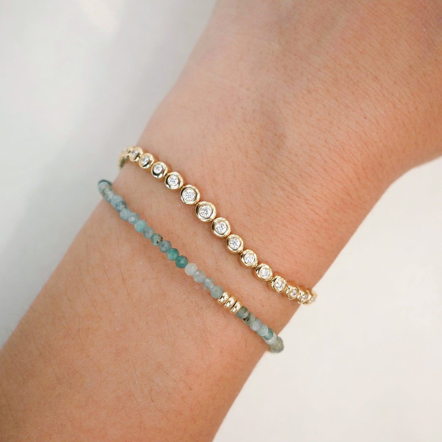 Ombré Tourmaline Birthstone Bead Bracelet in 14k yellow gold styled on wrist of model with graduated diamond pillow bracelet