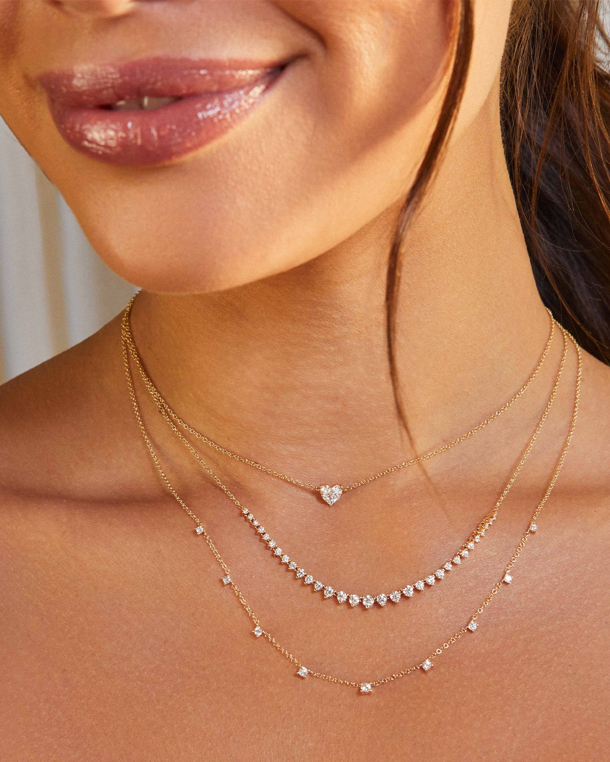 Graduated Diamond Necklace in 14k yellow gold styled on neck of model with full cut heart necklace and 9 prong diamond necklace