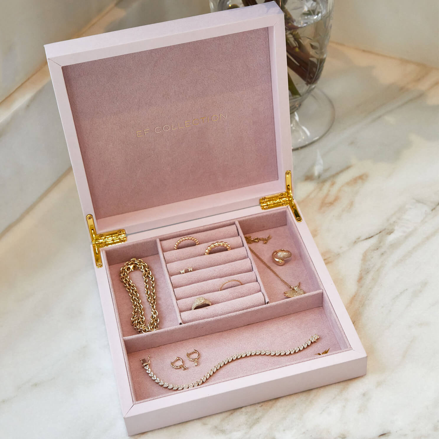 Signature Jewelry Box in the color pink displayed with 14k yellow gold rings, bracelets, earrings, and necklaces