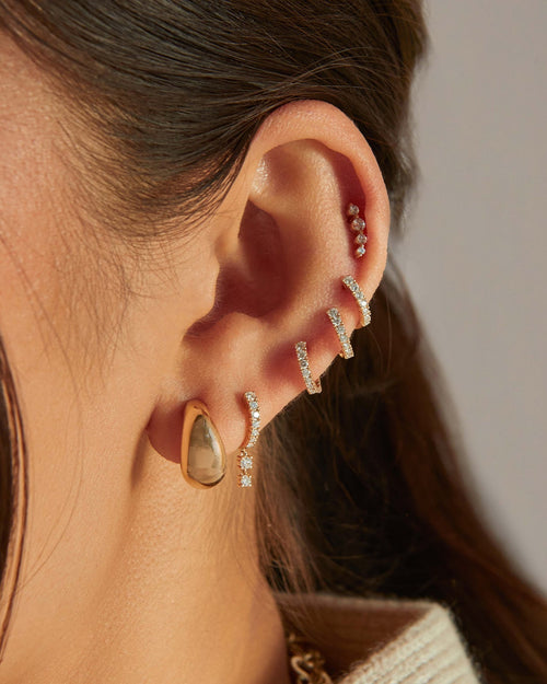 Prong Set Double Drop Huggie Earring in 14k yellow gold styled on ear of model with gold dome earring and four diamond earrings