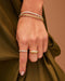 Prong Set Diamond Baguette Eternity Bracelet in 14k yellow gold styled on wrist of model next to gold chain bracelet and two rings styled on fingers