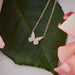 Diamond Flutter Necklace in 14k yellow gold on green leaf