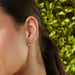 Full Cut Diamond Mini Teardrop Stud Earring in 14k yellow gold styled on third earring hole of model next to gold hummingbird earring, triple treasure earring, and sparkle stud earring