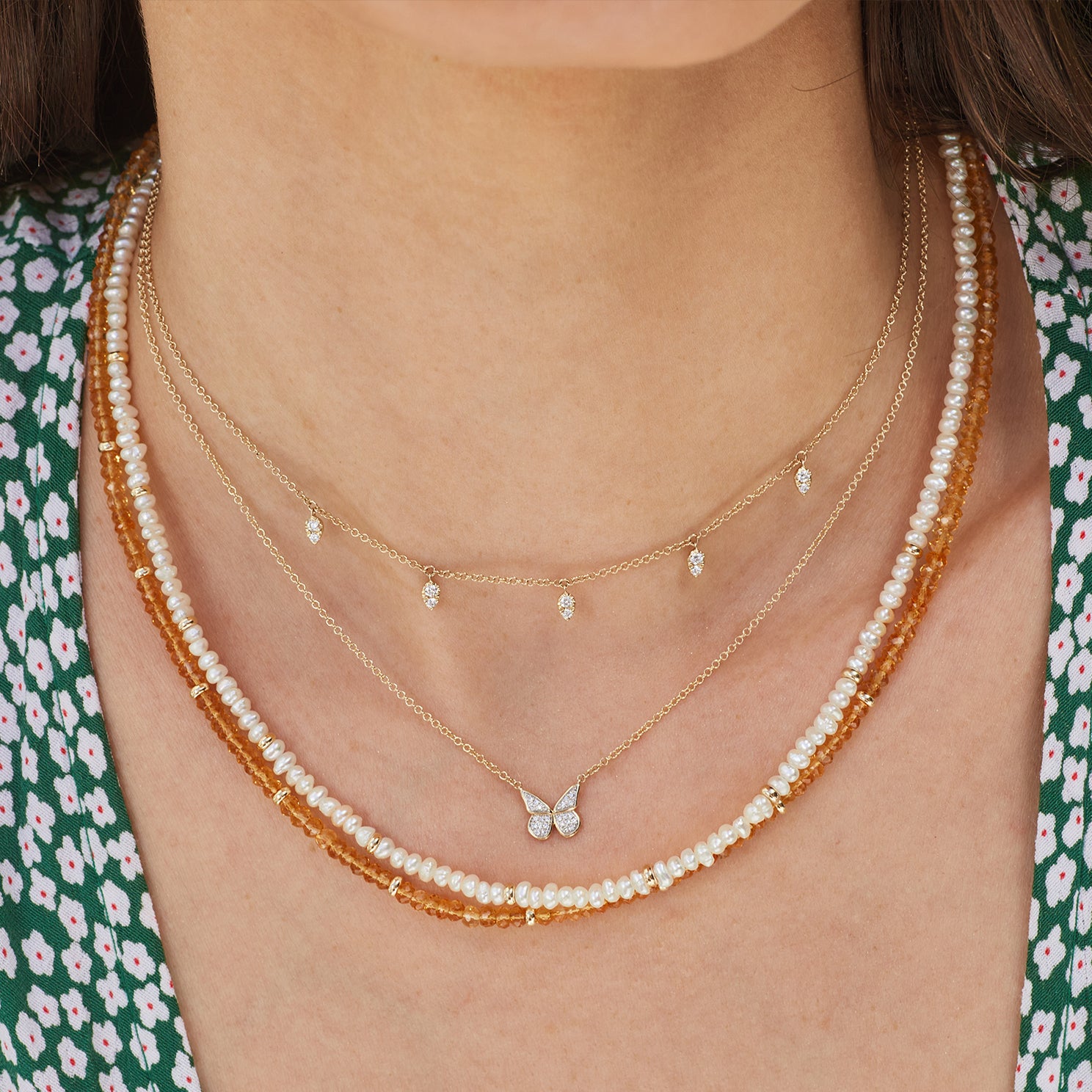 Diamond Flutter Necklace in 14k yellow gold styled on neck of model with diamond and gold necklace and two beaded necklaces