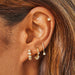 Diamond Bezel Shimmy Huggie Earring styled on ear of model with diamond and gold earrings