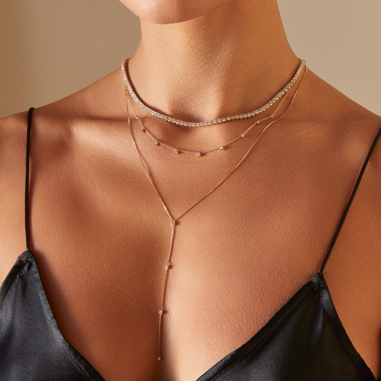9 Prong Set Diamond Necklace in 14k yellow gold styled on neck of model with diamond tennis necklace and diamond lariat necklace
