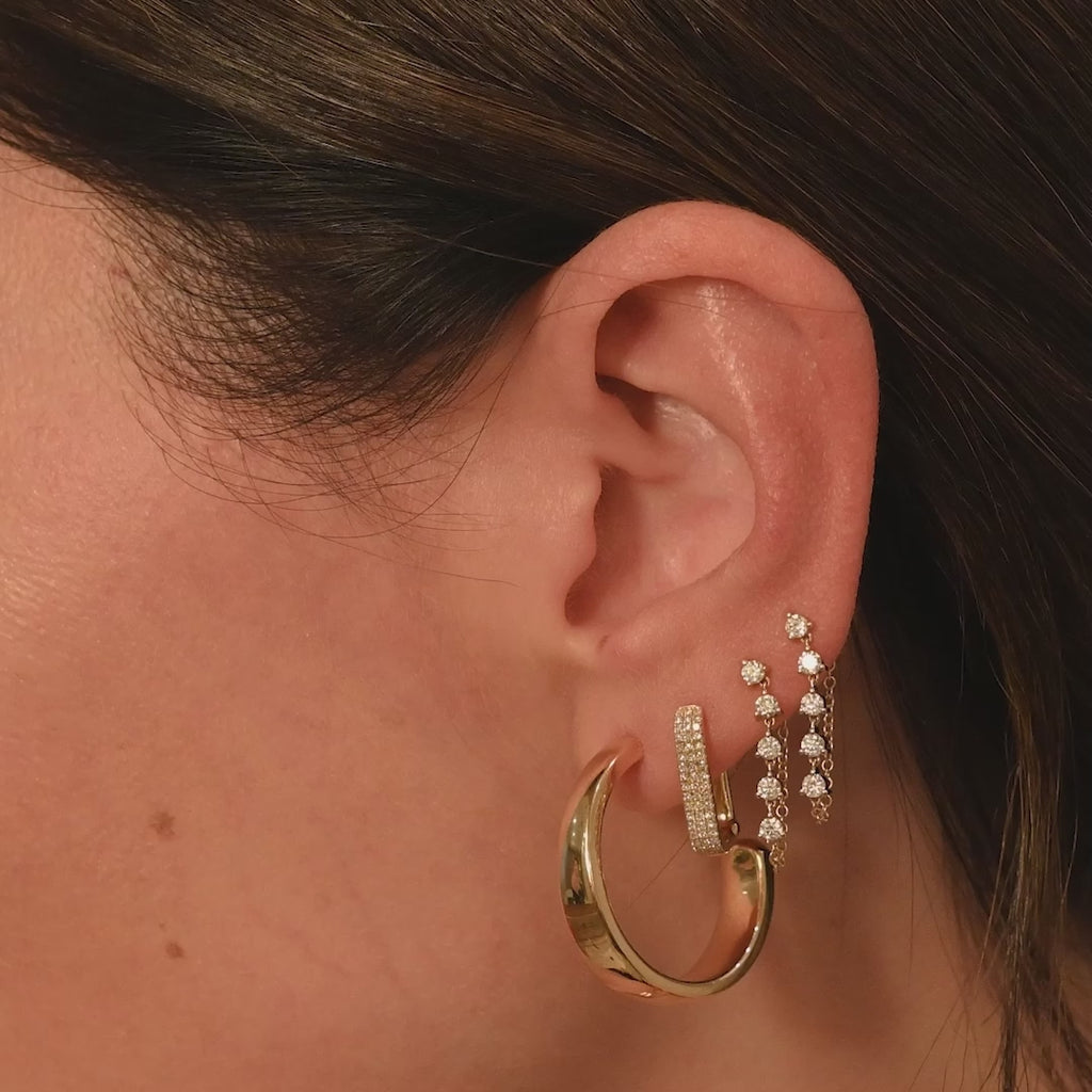 Tapered Gold Hoop Earrings in 14k yellow gold styled on first earring hole of model styled with Jumbo lola Hoop earring in second hole and multi diamond chain stud earring styled in third and fourth earring hole with no audio