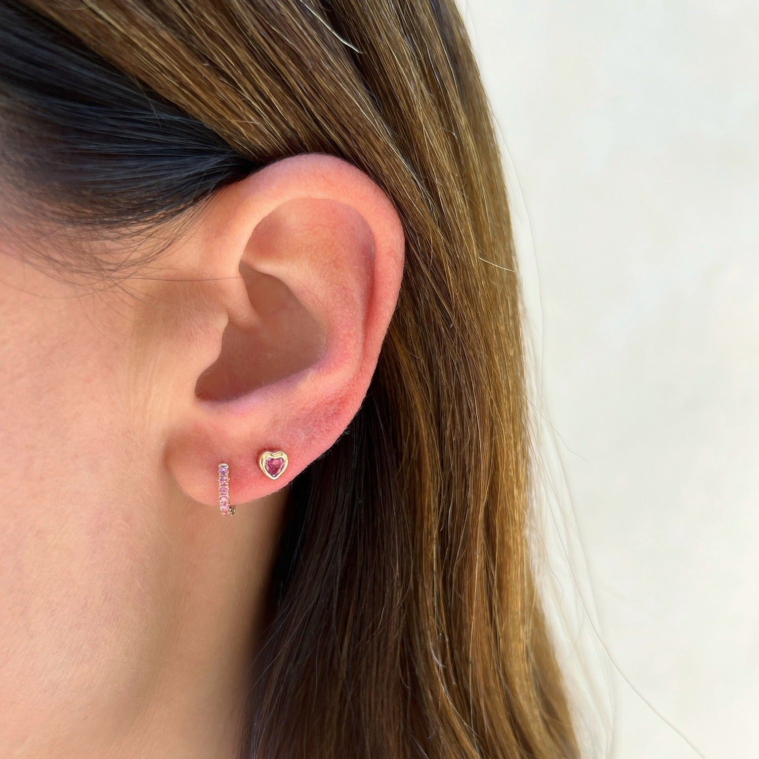 Pink Sapphire Mini Huggie Earring in 14k yellow gold styled on first earring hole on earlobe of model