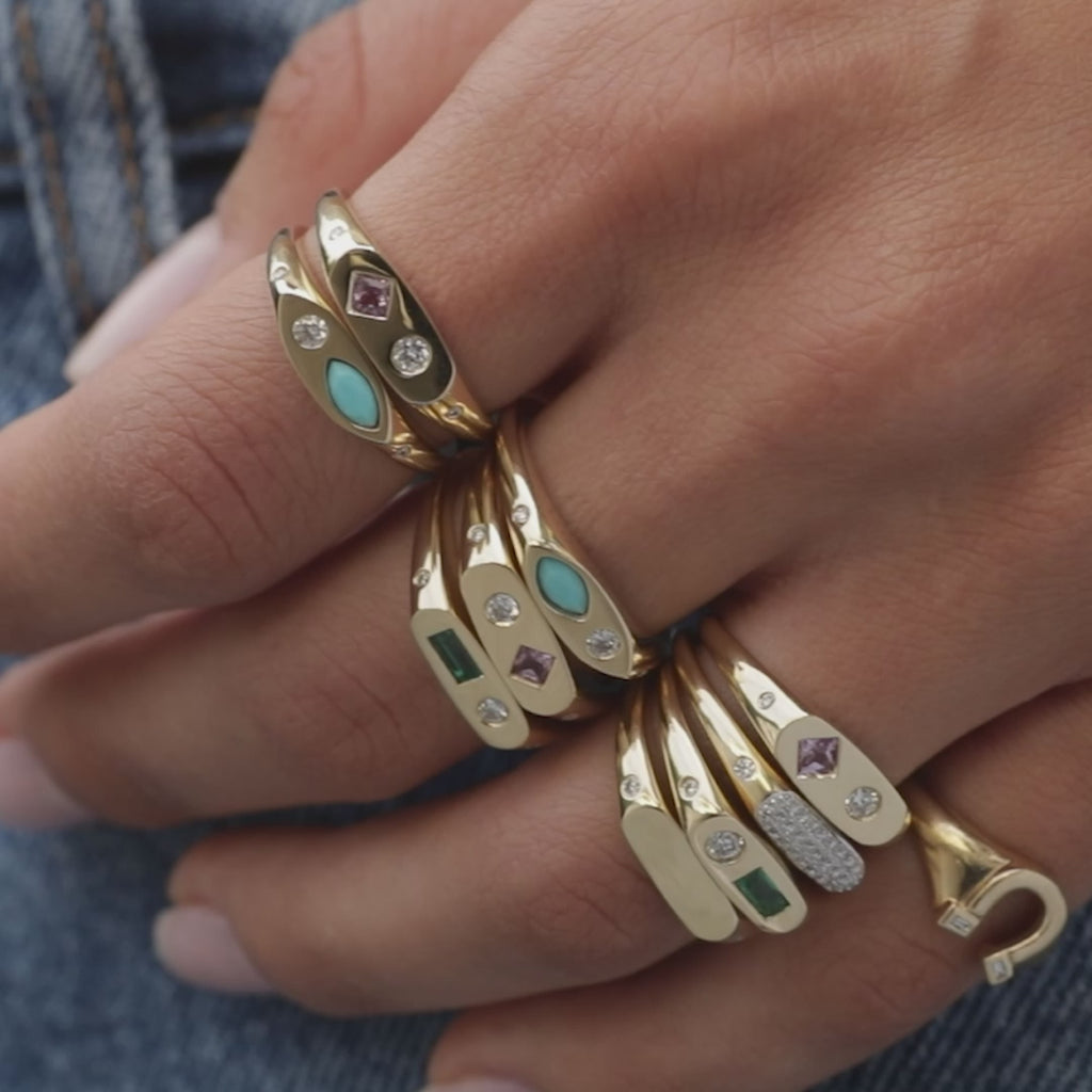 Gold Ring with Diamond Detail styled on ring finger stacked with three gold rings with gems and six additional rings on other fingers with no audio