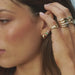 Triple Treasure Stud Earring in 14k yellow gold styled on second earring hole on ear lobe of model wearing three additional earrings with no audio