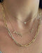 Double Diamond Script Name Necklace in 14k yellow gold with names griffin and zoe styled on neck of model wearing a gold jumbo chain necklace and a heart pendant necklace