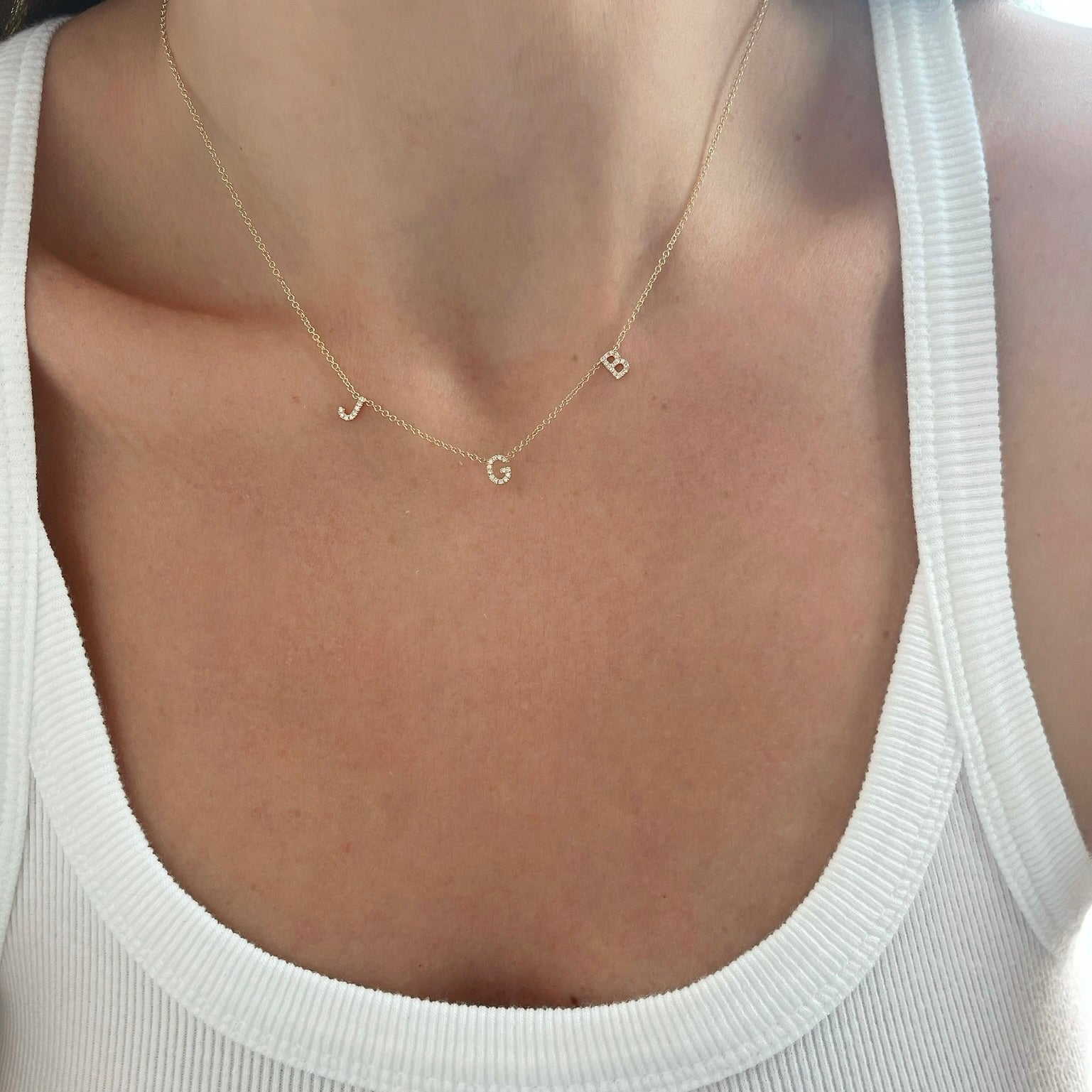Diamond Triple Initial Necklace styled on the neck in yellow gold