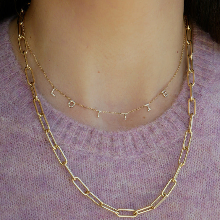 Diamond Multi Initial Necklace in 14k yellow gold styled on neck of model in initials LOTTIE model wearing gold chain and pink sweater