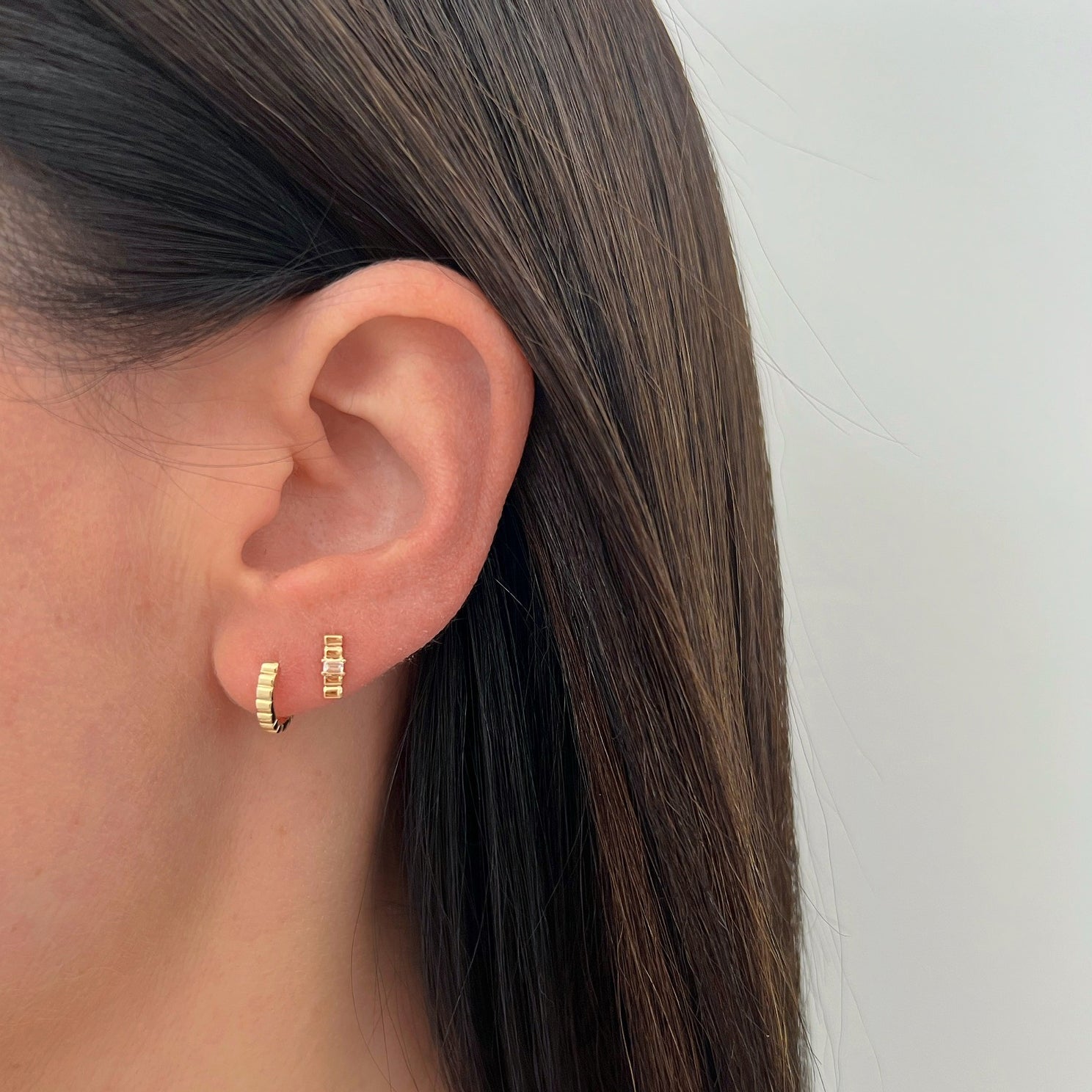 Diamond & Gold Fluted Bar Stud Earring in 14k yellow gold styled on second earring hole on ear lobe of model next to fluted huggie earring