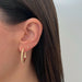 Gold Fluted Hoop Earrings in 14k yellow gold styled on ear lobe of model next to starburst diamond earring