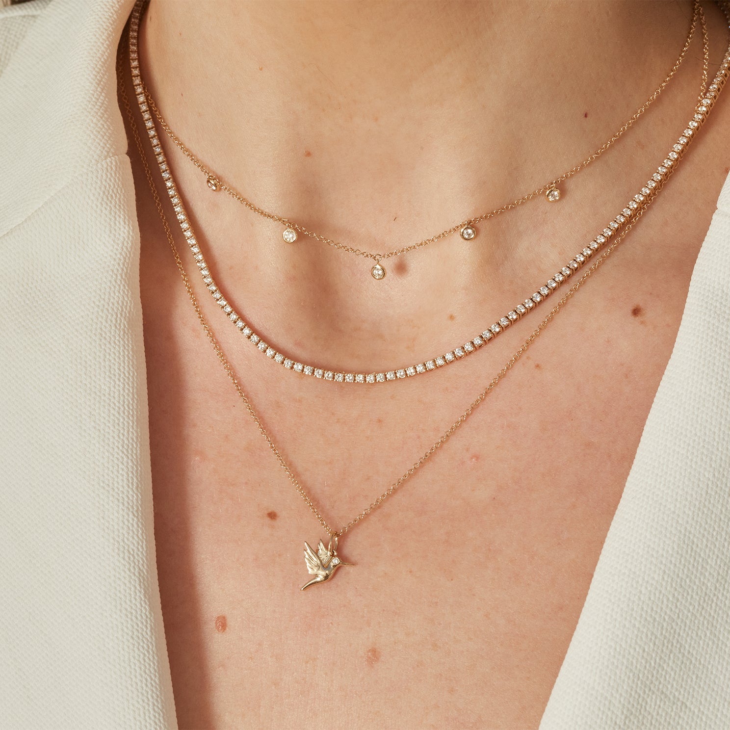 5 Diamond Bezel Choker Necklace in 14k yellow gold styled on neck of model with diamond necklace and hummingbird necklace