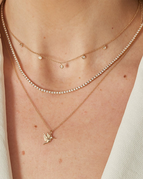 5 Diamond Bezel Choker Necklace in 14k yellow gold styled on neck of model with diamond necklace and hummingbird necklace
