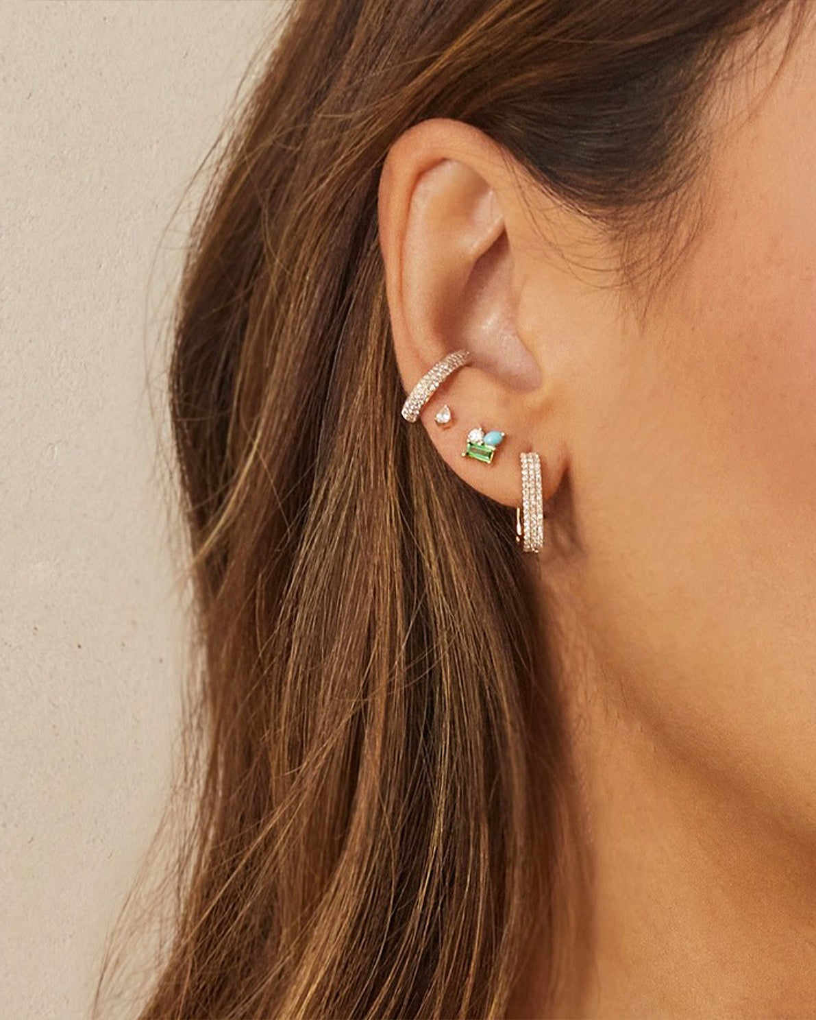 Triple Diamond Ear Cuff in 14k yellow gold styled on ear of model next to three earrings