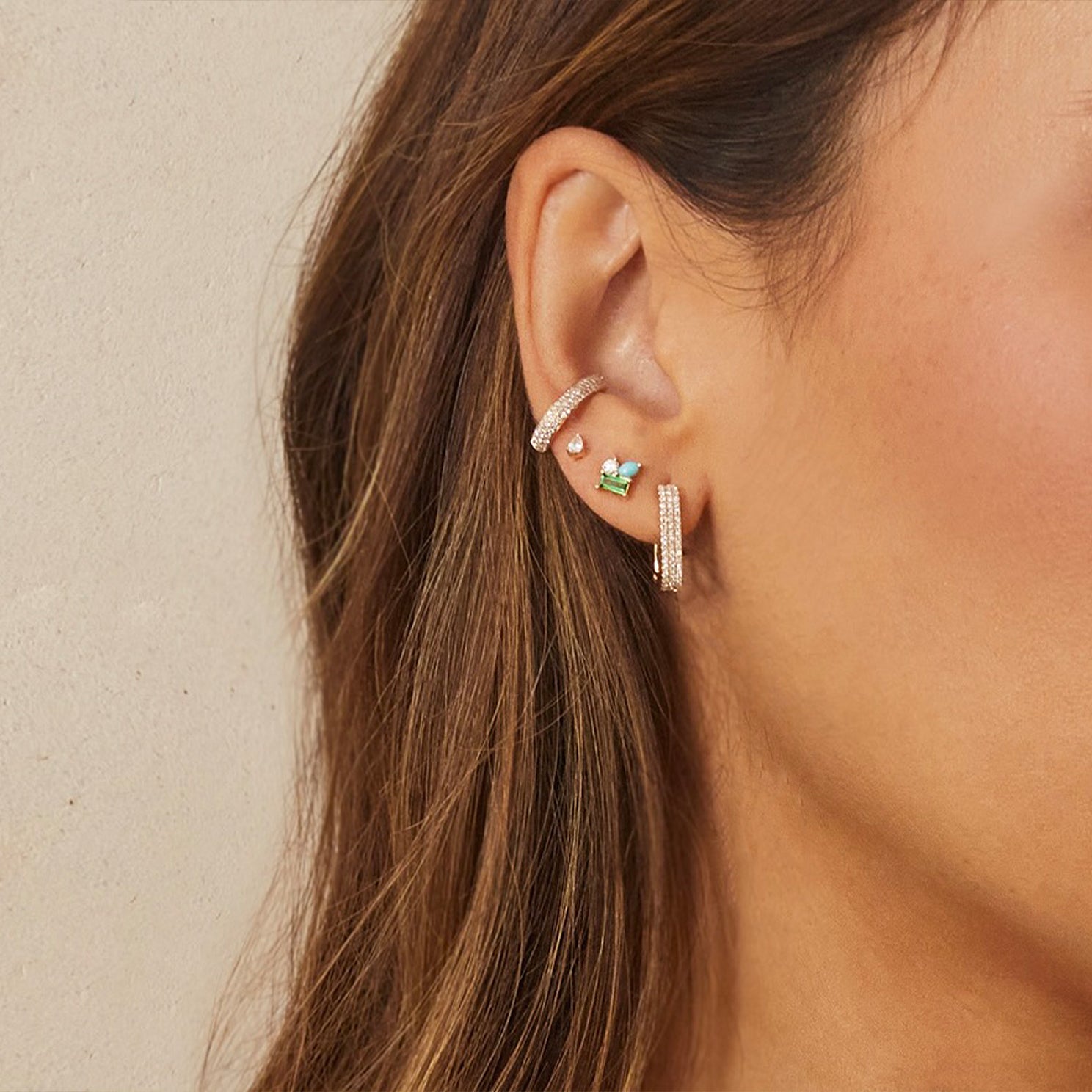 Triple Diamond Ear Cuff in 14k yellow gold styled on ear of model next to three earrings