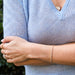 Diamond Grace tennis Bracelet styled on wrist of model in blue sweater