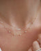 Diamond Multifaceted Mini Bar Necklace in 14k yellow gold styled on neck of model with 9 prong diamond necklace