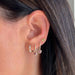 Diamond Mini Huggie with Pink Sapphire Heart Drop Earring in 14k yellow gold styled on second and third hole of earlobe of model with heart stud and diamond huggie earring