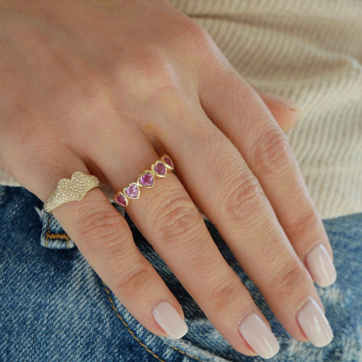Pink Sapphire Multi Heart Ring in 14k yellow gold styled on ring finger of model styled with diamond heart signet ring on pinky ring on hand of model