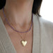 Birthstone Bead Necklace In Amethyst styled on neck of model with gold heart locket necklace and wearing tan sweater