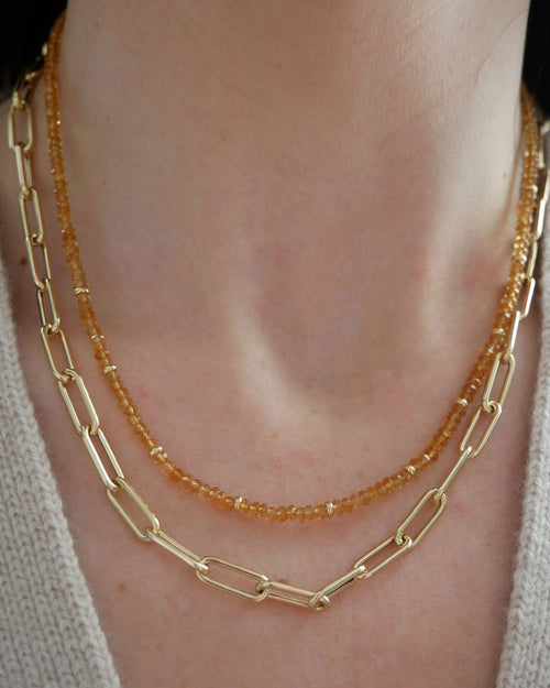 Birthstone Bead Necklace In Citrine styled on neck of model with jumbo lola chain gold necklace and wearing sweater