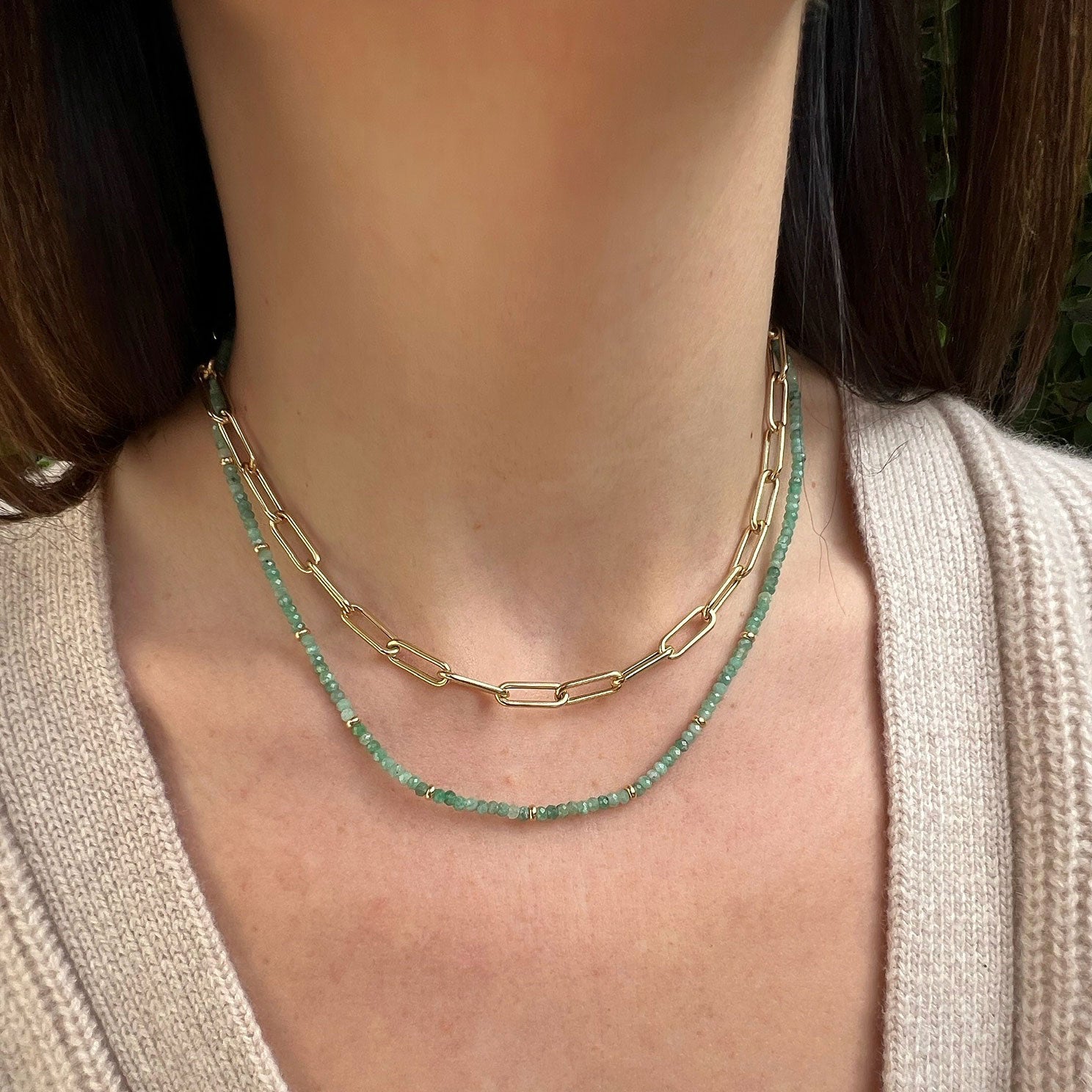 Birthstone Bead Necklace In Emerald styled on neck with 14k yellow gold jumbo chain necklace and wearing tan sweater