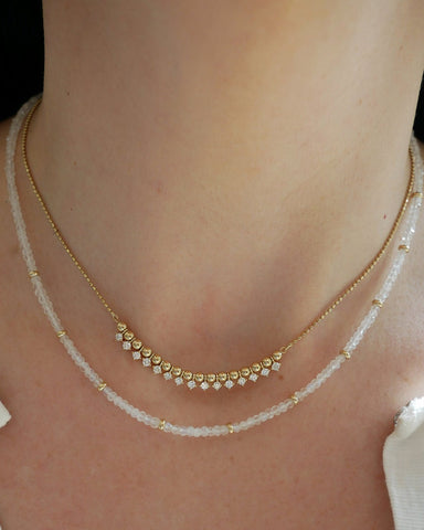 Birthstone Bead Necklace In Moon Stone styled on neck of model with gold and diamond segment necklace