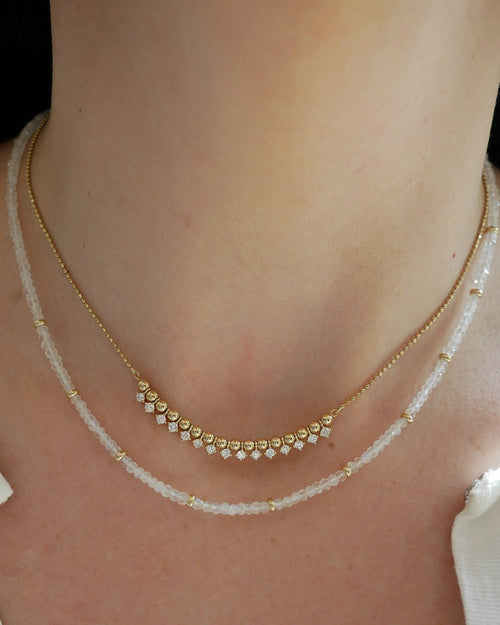 Birthstone Bead Necklace In Moon Stone styled on neck of model with gold and diamond segment necklace