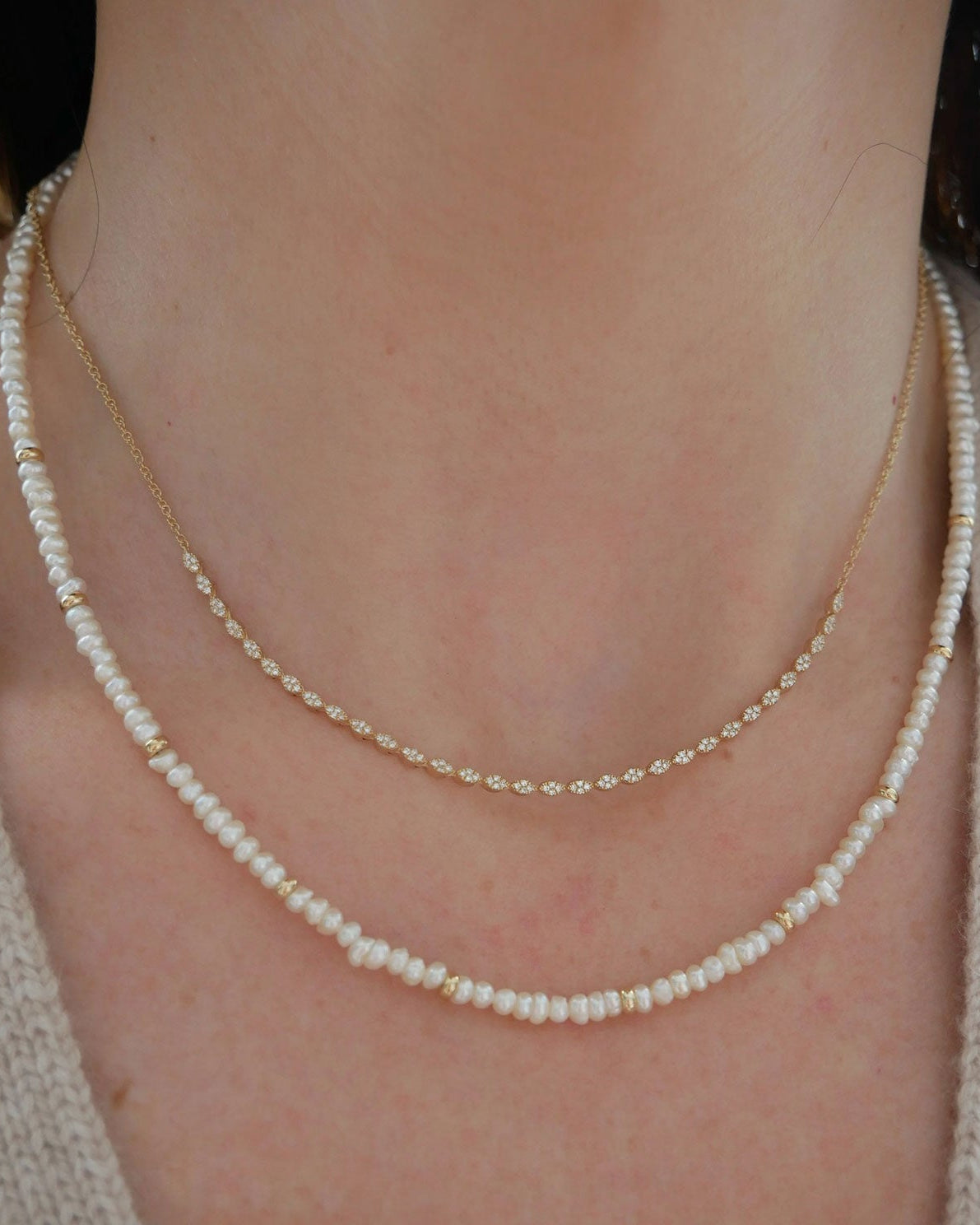 Birthstone Bead Necklace In Pearl styled on neck of model with diamond marquise necklace and wearing tan sweater