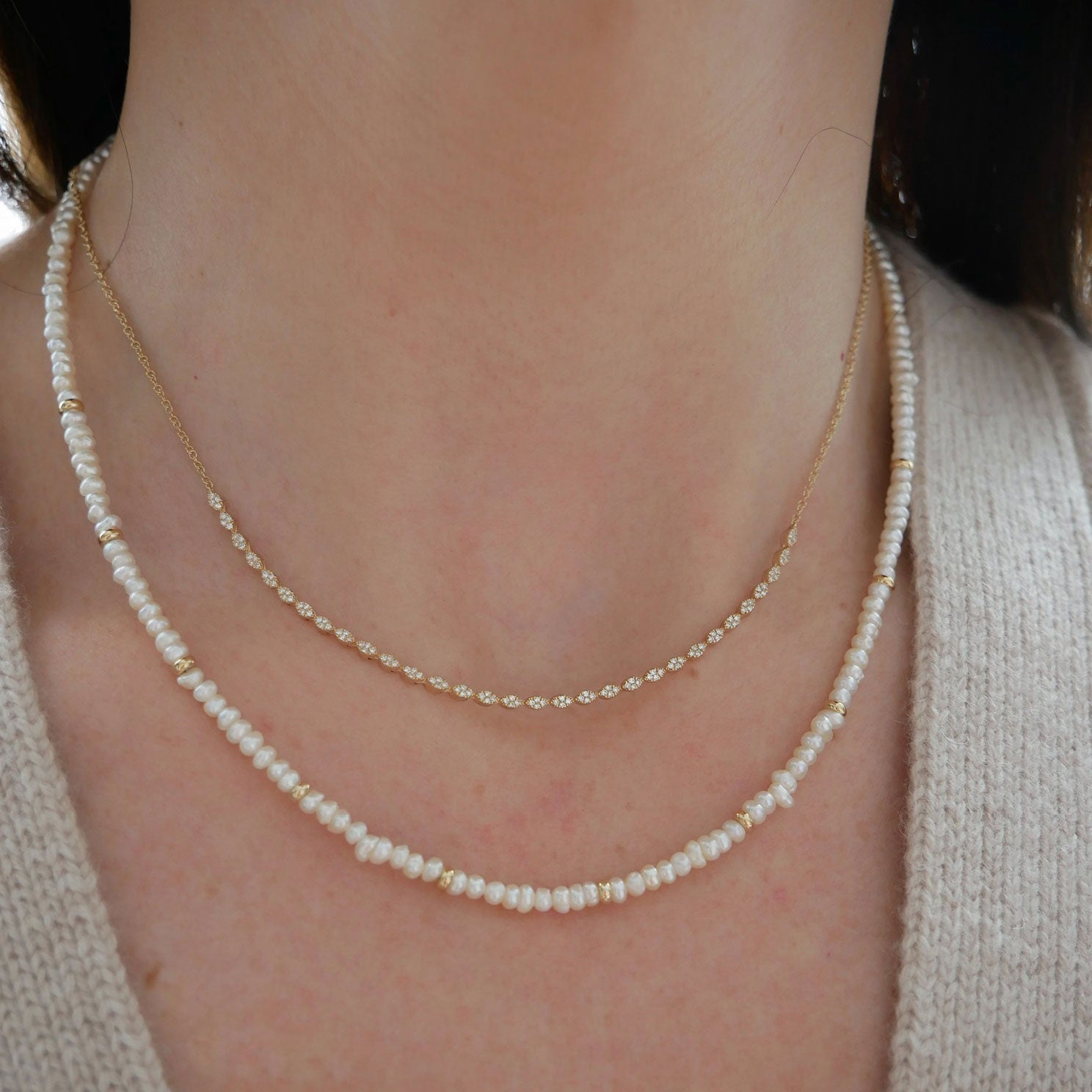 Birthstone Bead Necklace In Pearl styled on neck of model with diamond marquise necklace and wearing tan sweater
