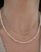 Birthstone Bead Necklace In Pearl styled on neck of model with diamond marquise necklace and wearing tan sweater