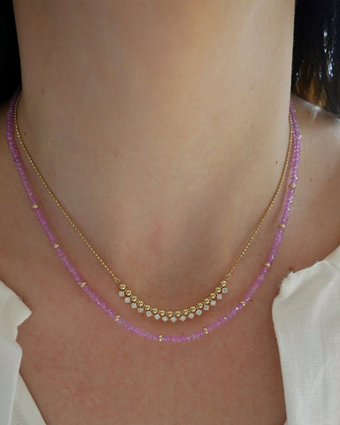 Birthstone Bead Necklace In Pink Sapphire styled on neck with diamond and gold ball necklace wearing a white blouse