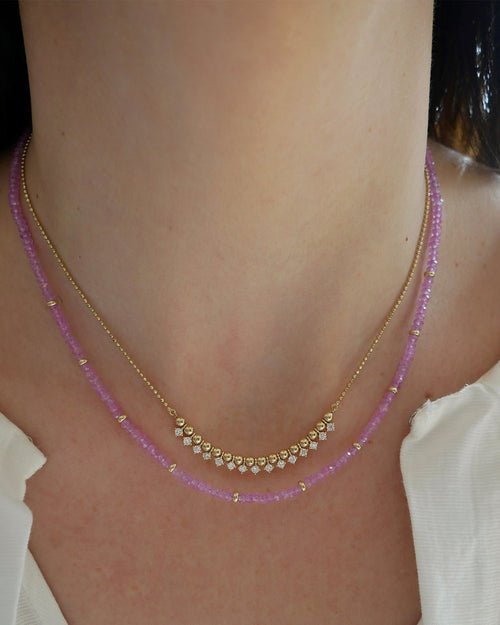 Birthstone Bead Necklace In Pink Sapphire styled on neck with diamond and gold ball necklace wearing a white blouse
