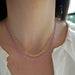 Birthstone Bead Necklace In Pink Sapphire styled on neck with diamond and gold ball necklace wearing a white blouse