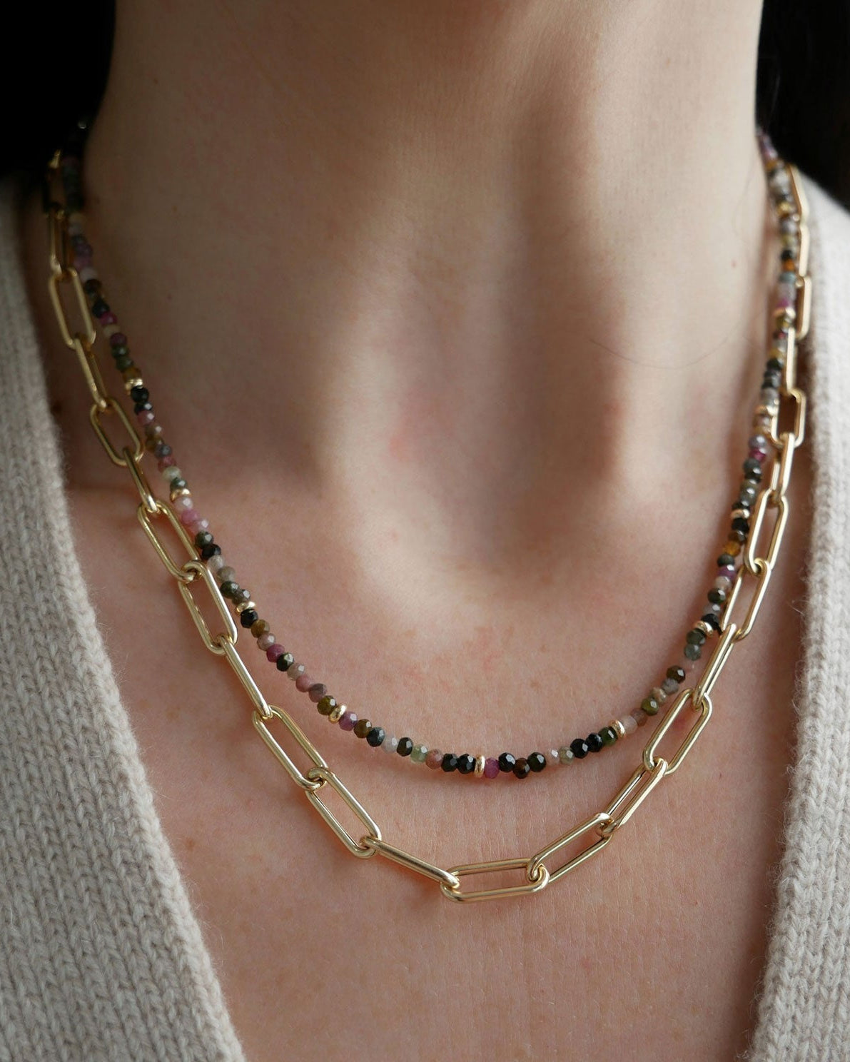 Birthstone Bead Necklace In Tourmaline styled on neck of model wearing jumbo lola chain necklace in 14k yellow gold and wearing tan sweater