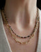 Birthstone Bead Necklace In Tourmaline styled on neck of model wearing jumbo lola chain necklace in 14k yellow gold and wearing tan sweater
