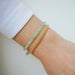 Birthstone Bead Bracelet In Chalcedony styled on wrist with gold ball stretch bracelet on model wearing white sleeve