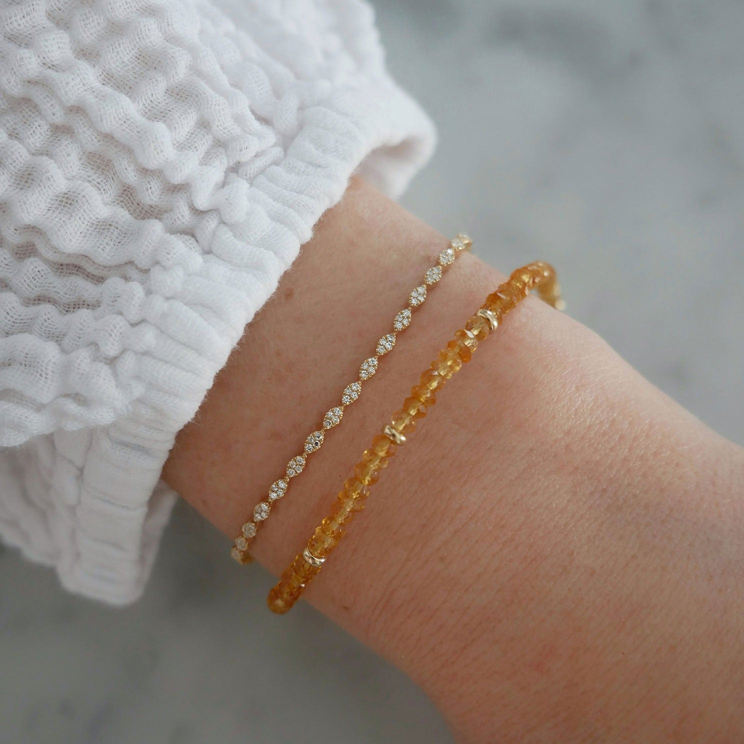 Birthstone Bead Bracelet In Citrine styled on wrist of model with diamond marquise bracelet and white sleeve