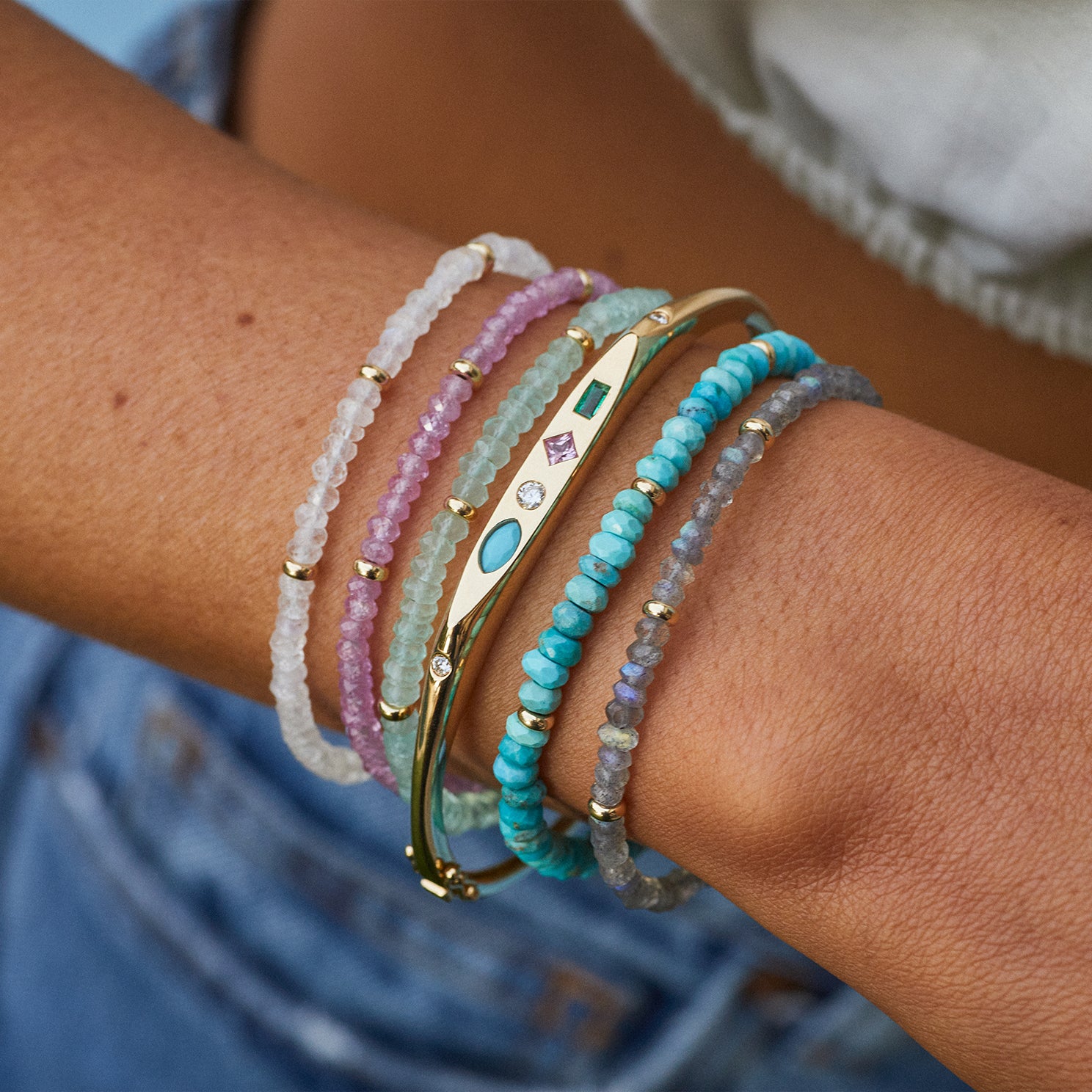 Birthstone Bead Bracelet In Chalcedony styled on wrist of model with four additional beaded bracelets and gold treasure bangle bracelet