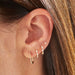 Baby Solitaire Diamond Stud Earring in 14k yellow gold styled on fourth earring hole on ear lobe of model with brown hair
